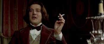 Movie still from “Wilde” (1997), directed by Brian Gilbert – A man holding a cigarette in his right hand; Close Up shot, Low angle