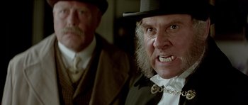 Movie still from “Wilde” (1997), directed by Brian Gilbert – A man in a top hat and a beard; Close Up shot, Over the shoulder angle