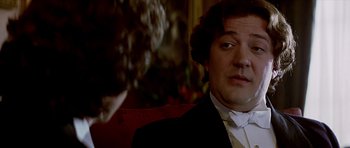 Movie still from “Wilde” (1997), directed by Brian Gilbert – A person wearing a suit and tie; Close Up shot, Over the shoulder angle