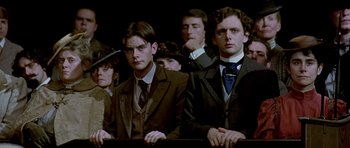 Movie still from “Wilde” (1997), directed by Brian Gilbert – A group of men and women in suits and ties; Medium shot, Low angle