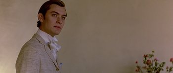 Movie still from “Wilde” (1997), directed by Brian Gilbert – A man in a suit and tie looking at the camera; Close Up shot, Over the shoulder angle