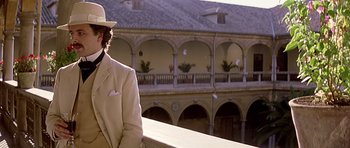 Movie still from “Wilde” (1997), directed by Brian Gilbert – A man in a white suit and a white hat standing in front of a building; Medium shot, Low angle