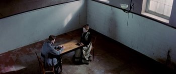 Movie still from “Wilde” (1997), directed by Brian Gilbert – A man and woman sitting at a table in a room; Wide shot, High angle