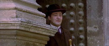 Movie still from “Wilde” (1997), directed by Brian Gilbert – A man wearing a hat and a suit and tie; Close Up shot, Low angle