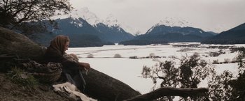 Movie still from “Willow” (1988), directed by Ron Howard – A bird sitting on a tree branch in front of snow covered mountains; Wide shot, Low angle
