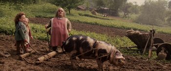 Movie still from “Willow” (1988), directed by Ron Howard – A woman is standing next to a pig in a field; Medium shot, Low angle