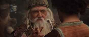 Movie still from “Willow” (1988), directed by Ron Howard – An old man with long white hair and a beard; Close Up shot, Over the shoulder angle