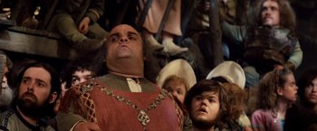 Movie still from “Willow” (1988), directed by Ron Howard – A group of people sitting in a room; Medium shot, Low angle