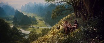 Movie still from “Willow” (1988), directed by Ron Howard – A man and a woman on a hill with a river in the background; Extreme Wide shot, High angle