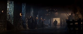 Movie still from “Willow” (1988), directed by Ron Howard – A group of people standing in a dark room; Wide shot, High angle