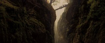 Movie still from “Willow” (1988), directed by Ron Howard – A group of people standing on a bridge over a river; Extreme Wide shot, Overhead angle