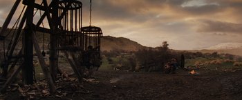 Movie still from “Willow” (1988), directed by Ron Howard – An old cage hanging from a chain in the middle of a dirt field; Wide shot, Low angle