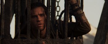 Movie still from “Willow” (1988), directed by Ron Howard – A person behind a metal fence; Close Up shot, Low angle