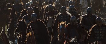 Movie still from “Willow” (1988), directed by Ron Howard – A group of people in helmets are walking through a field; Wide shot, High angle