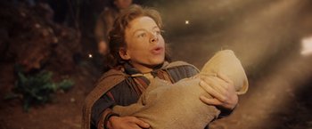 Movie still from “Willow” (1988), directed by Ron Howard – A young man holding a bag in his hands; Medium shot, High angle