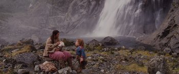 Movie still from “Willow” (1988), directed by Ron Howard – Two women and a child sitting in front of a waterfall; Wide shot, Low angle