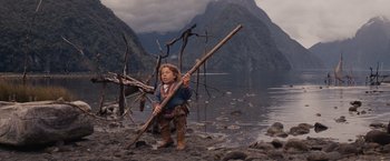 Movie still from “Willow” (1988), directed by Ron Howard – A young boy is holding a stick in his hand; Wide shot, Low angle