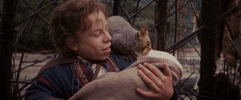 Movie still from “Willow” (1988), directed by Ron Howard – A woman holding a book with a squirrel on her shoulder; Medium shot, High angle