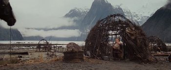 Movie still from “Willow” (1988), directed by Ron Howard – A person sitting in front of a hut made out of sticks; Wide shot, Low angle