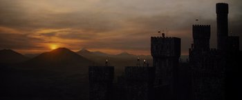 Movie still from “Willow” (1988), directed by Ron Howard – A view of a sunset from the top of a castle; Extreme Wide shot, Low angle