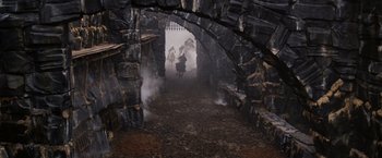 Movie still from “Willow” (1988), directed by Ron Howard – A group of people walking through a stone tunnel; Extreme Wide shot, High angle