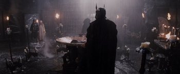 Movie still from “Willow” (1988), directed by Ron Howard – A man in a black robe stands in front of a table in the rain; Wide shot, High angle