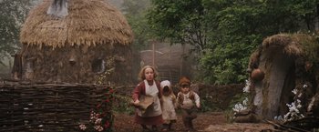 Movie still from “Willow” (1988), directed by Ron Howard – Three children dressed in costumes stand in front of a hut; Wide shot, Low angle