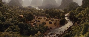 Movie still from “Willow” (1988), directed by Ron Howard – An aerial view of an area with a river and mountains in the background; Extreme Wide shot, High angle