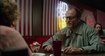 Movie still from “Wilson” (2017), directed by Craig Johnson – A man sitting at a table in front of a milkshake; Medium shot, Over the shoulder angle