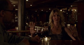Movie still from “Wilson” (2017), directed by Craig Johnson – A woman sitting at a table in front of a glass of red wine; Medium shot, Over the shoulder angle