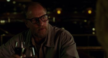 Movie still from “Wilson” (2017), directed by Craig Johnson – An older man with glasses sitting at a table with a glass of wine in front of him; Close Up shot, Over the shoulder angle