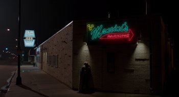 Movie still from “Wilson” (2017), directed by Craig Johnson – A person standing in front of a building at night; Extreme Wide shot, Over the shoulder angle