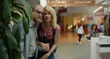 Movie still from “Wilson” (2017), directed by Craig Johnson – A man and a woman standing next to each other in a mall; Medium shot, Low angle