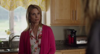 Movie still from “Wilson” (2017), directed by Craig Johnson – A woman standing in a kitchen wearing a pink sweater; Medium shot, Over the shoulder angle