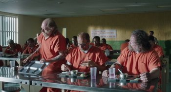 Movie still from “Wilson” (2017), directed by Craig Johnson – A group of men in orange jumpsuits eating food; Wide shot, High angle