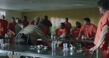 Movie still from “Wilson” (2017), directed by Craig Johnson – A group of men in orange jumpsuits are sitting at a table; Wide shot, Over the shoulder angle
