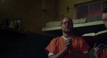Movie still from “Wilson” (2017), directed by Craig Johnson – A man in an orange prison uniform is praying; Medium shot, Low angle