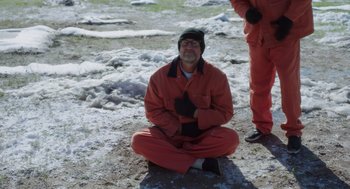 Movie still from “Wilson” (2017), directed by Craig Johnson – A man sitting on the ground wearing an orange suit; Wide shot, High angle