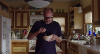 Movie still from “Wilson” (2017), directed by Craig Johnson – A man in a blue shirt is stirring a bowl in a kitchen; Medium shot, Low angle