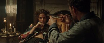 Movie still from “Winchester” (2018), directed by Michael Spierig – A woman sitting in front of a mirror while a man takes a picture of her; Medium shot, Over the shoulder angle