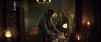 Movie still from “Winchester” (2018), directed by Michael Spierig – A man pouring tea into a cup while another man watches; Medium shot, Low angle