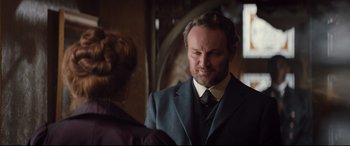 Movie still from “Winchester” (2018), directed by Michael Spierig – A man wearing a suit and tie standing next to a woman; Close Up shot, Over the shoulder angle