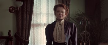 Movie still from “Winchester” (2018), directed by Michael Spierig – A woman with red hair wearing a black and white dress; Medium shot, Low angle