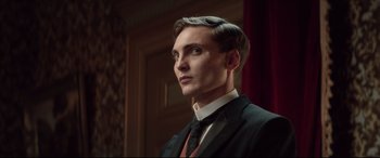 Movie still from “Winchester” (2018), directed by Michael Spierig – A man in a suit and tie looking to his left; Close Up shot, Low angle