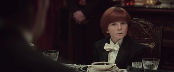 Movie still from “Winchester” (2018), directed by Michael Spierig – A boy in a tuxedo sitting at a table with a cup of coffee; Close Up shot, Over the shoulder angle