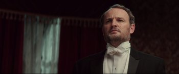 Movie still from “Winchester” (2018), directed by Michael Spierig – A man wearing a tuxedo and a white bow tie; Close Up shot, Low angle