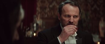 Movie still from “Winchester” (2018), directed by Michael Spierig – A person wearing a suit and tie; Close Up shot, Low angle