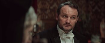 Movie still from “Winchester” (2018), directed by Michael Spierig – A man in a tuxedo is looking at the camera; Close Up shot, Over the shoulder angle