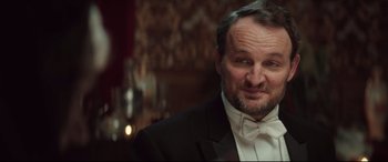 Movie still from “Winchester” (2018), directed by Michael Spierig – A person wearing a suit and bow tie; Close Up shot, Low angle