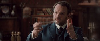 Movie still from “Winchester” (2018), directed by Michael Spierig – A man in a suit and tie holding a spoon in his hand; Close Up shot, Low angle